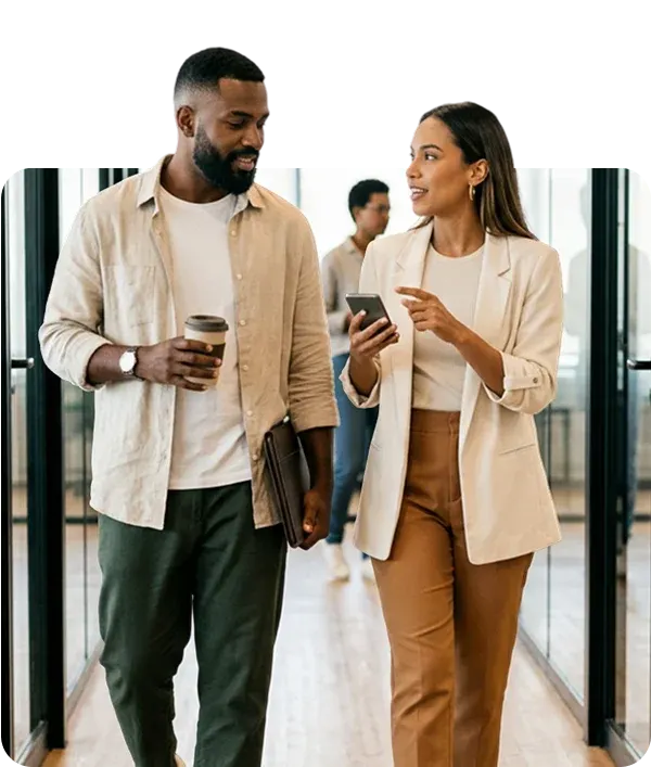 Dois profissionais conversando enquanto uma mulher consulta o smartphone no escritório