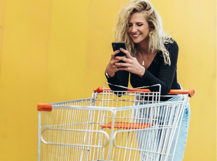 Imagem de uma mulher sorrindo apoiada em um carrinho de compras