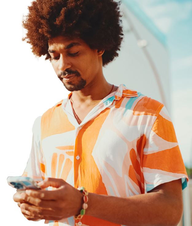 Foto de um homem segurando um smartphone em suas mãos, exibindo uma expressão de interesse enquanto interage com o dispositivo.